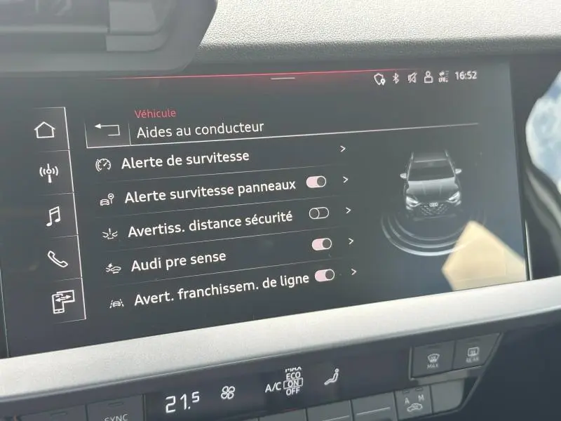 Écran tactile intérieur de l'Audi A3 Sportback blanc Arkona affichant les aides à la conduite et alertes de sécurité.