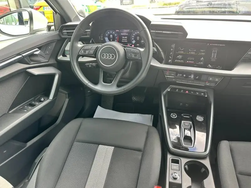 Vue intérieure avant de l'Audi A3 Sportback 2024, tableau de bord moderne avec écran tactile et volant cuir multifonction.