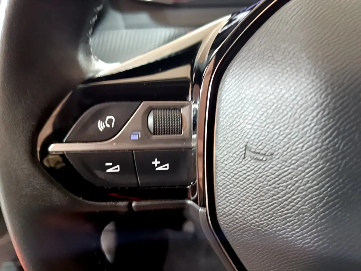 Gros plan sur les commandes gauche du volant cuir du Peugeot 2008 gris clair version BlueHDi 110 S&S Active 2022.