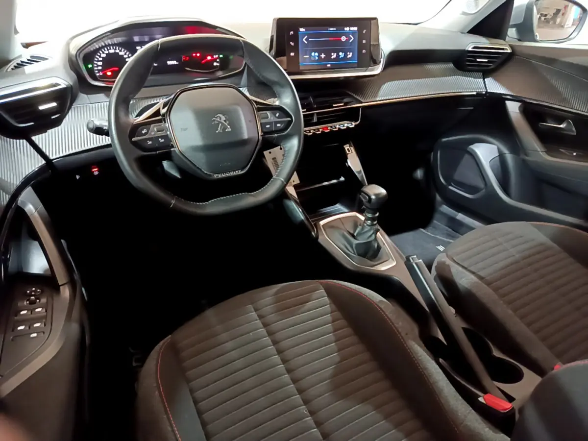 Intérieur de la Peugeot 2008 2022 vue côté conducteur, volant cuir, écran tactile et levier de vitesse manuel visibles.