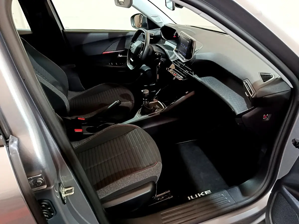 Intérieur côté conducteur du Peugeot 2008 gris clair 2022, avec tableau de bord moderne et écran tactile central.