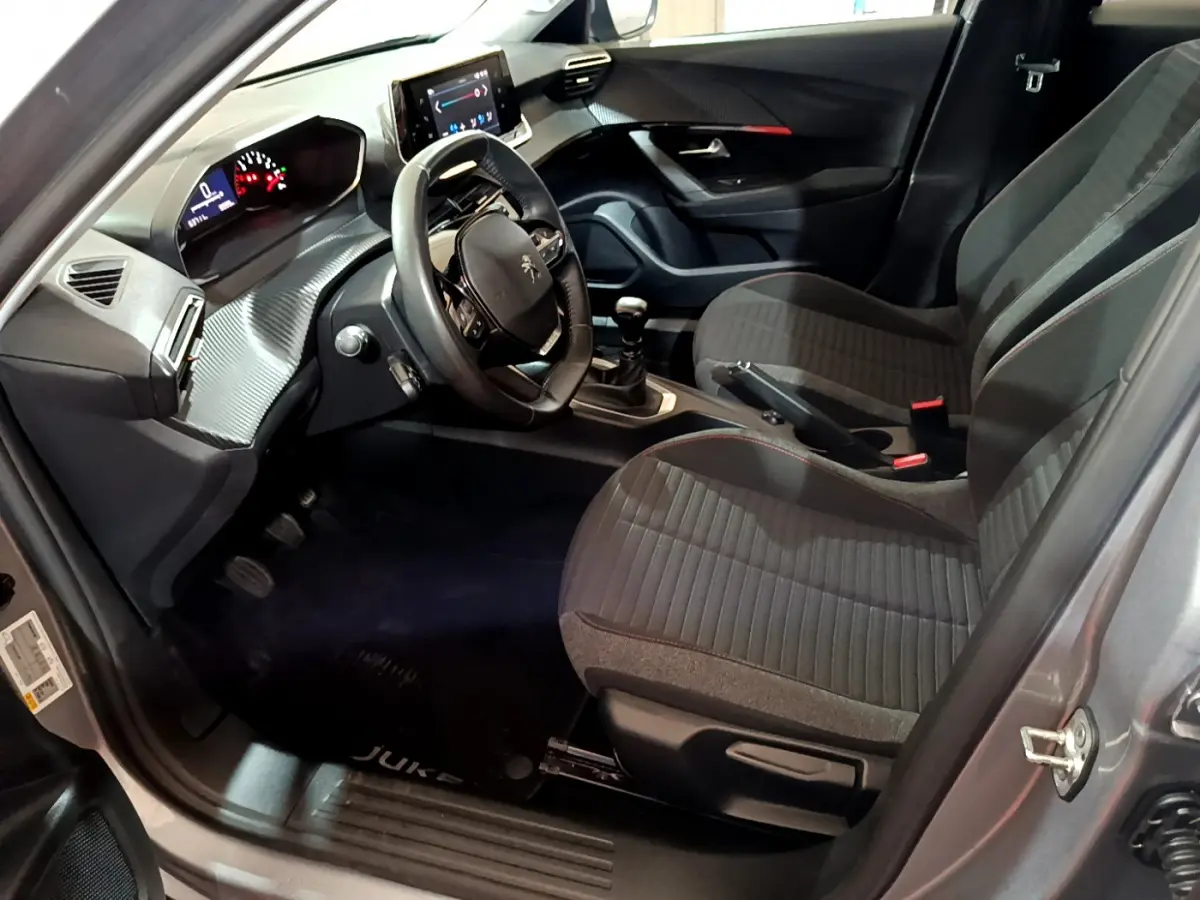 Intérieur avant droit du Peugeot 2008 gris clair 2022, volant cuir, tableau de bord numérique et écran tactile visible.