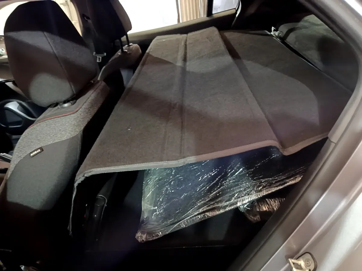 Vue intérieure arrière du Peugeot 2008 gris clair, banquette rabattue avec cache-bagages déployé.