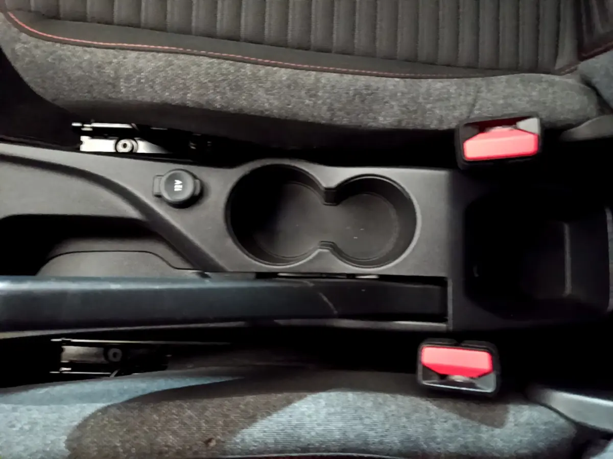 Gros plan sur la console centrale de la Peugeot 2008 gris clair, avec porte-gobelets et ceintures rouges visibles entre les sièges.