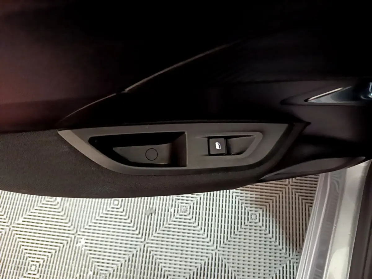 Gros plan sur la poignée intérieure et bouton de verrouillage de la porte côté conducteur d’un Peugeot 2008 gris clair 2022.