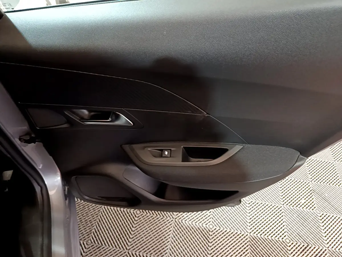 Gros plan sur la porte côté gauche gris clair du Peugeot 2008 2022 avec commande de lève-vitre et poignée intégrée.