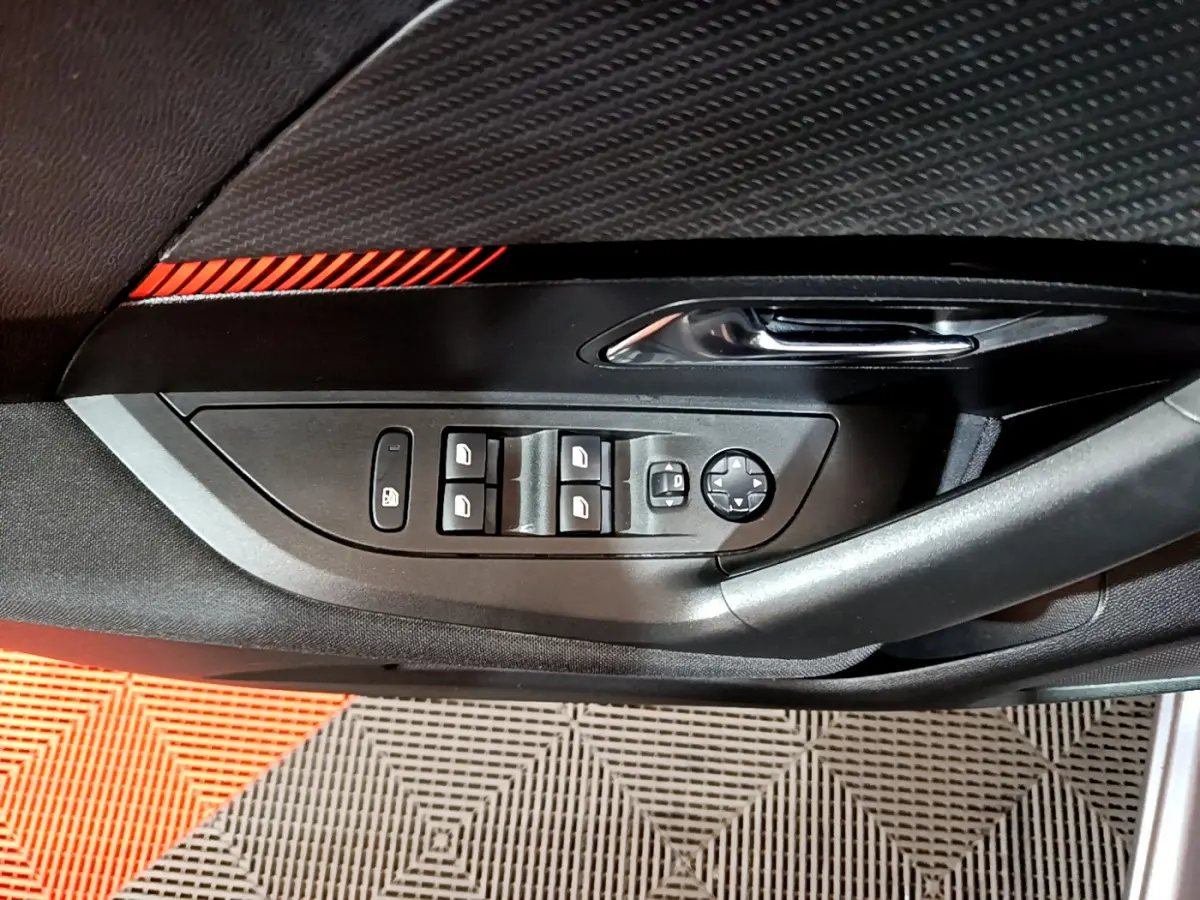 Gros plan sur la commande des vitres et rétroviseurs côté conducteur du Peugeot 2008 gris clair, intérieur noir.