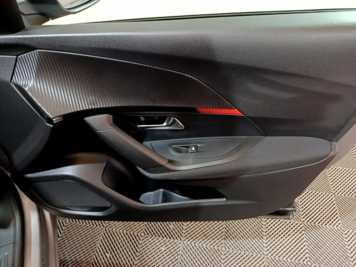 Gros plan sur la porte côté conducteur du Peugeot 2008 gris clair, avec insert décoratif noir et rouge.