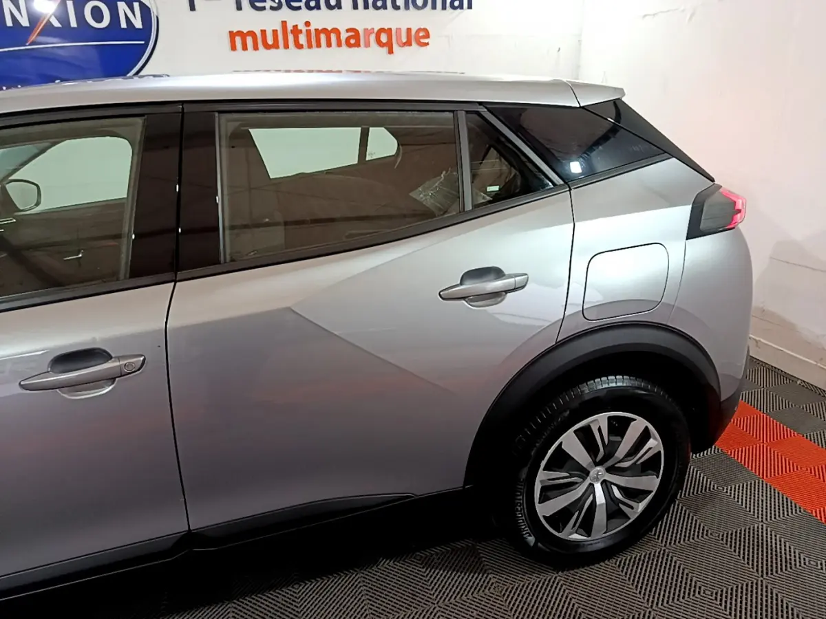 Vue latérale droite d'un Peugeot 2008 gris clair 2022, mettant en valeur la porte arrière et la roue arrière avec jante stylisée.