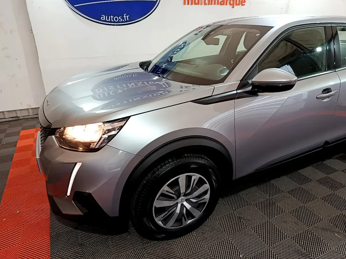 PEUGEOT 2008 gris clair vue 3/4 avant gauche avec phares allumés et jantes alliage distinctives.