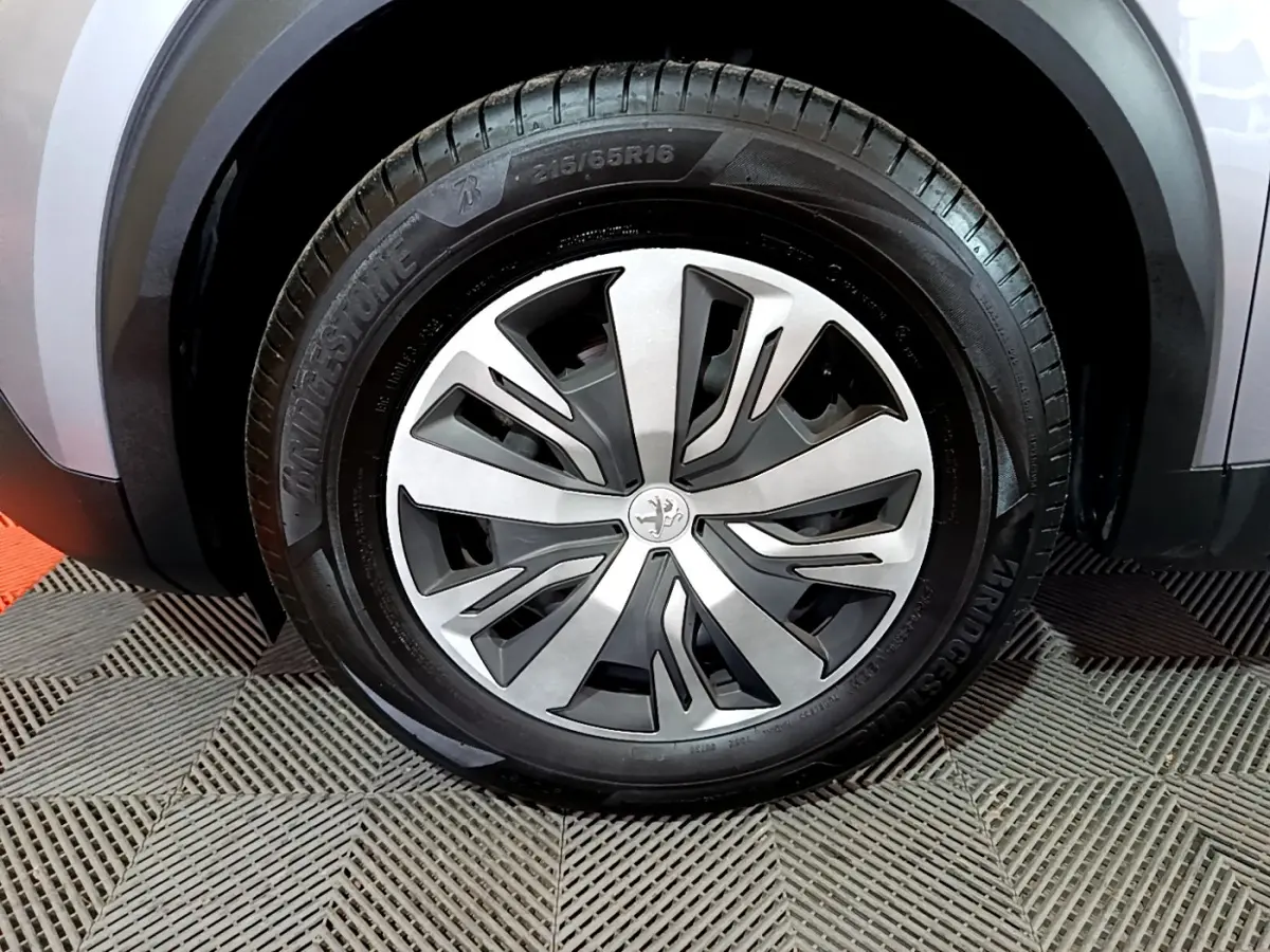 Gros plan sur la roue avant droite d’un Peugeot 2008 gris clair, avec jante alliage au design moderne.