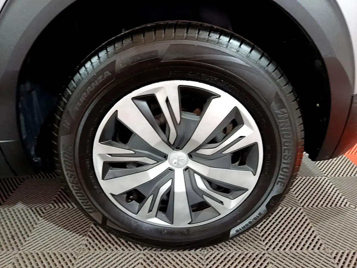 Gros plan sur la roue avant droite du Peugeot 2008 gris clair, mettant en valeur la jante moderne et le pneu Bridgestone.