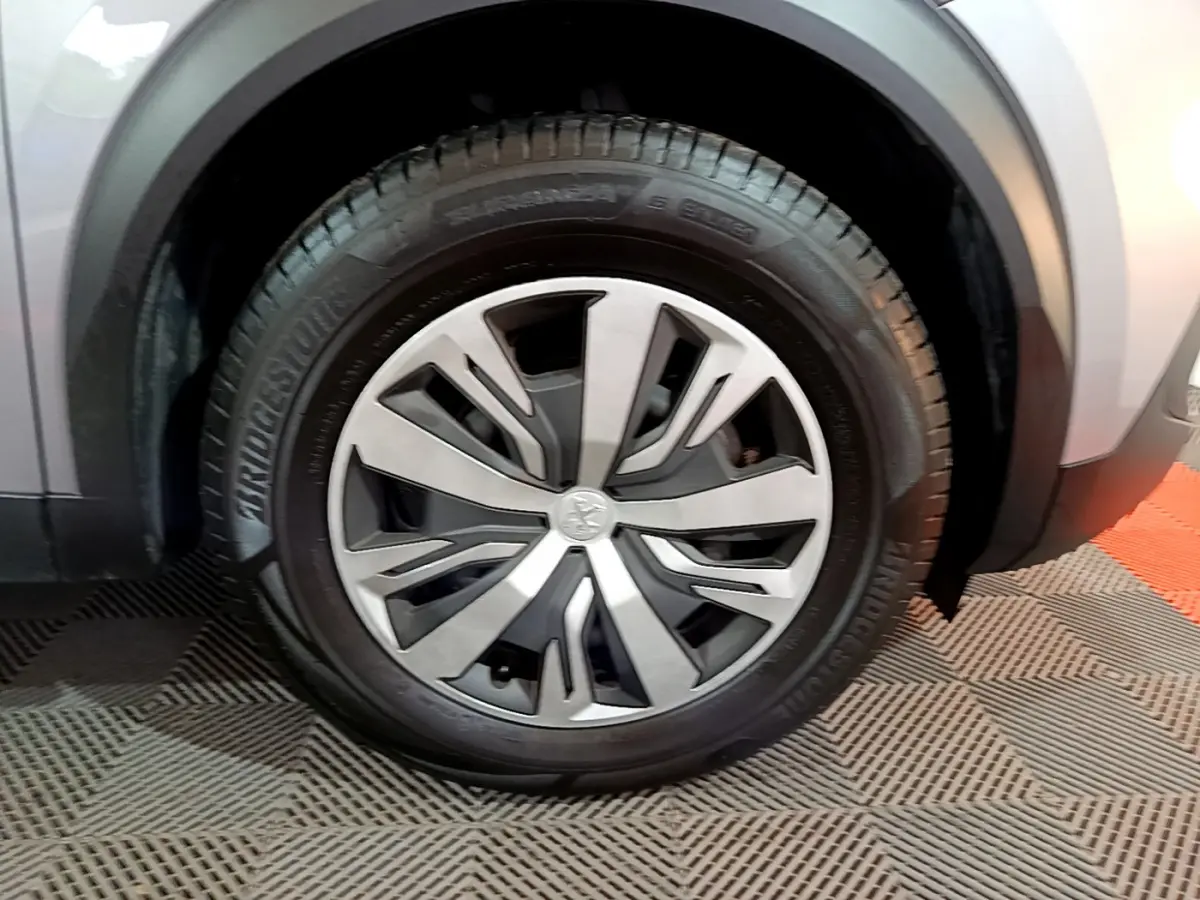 Gros plan sur la roue avant gauche du Peugeot 2008 gris clair, mettant en valeur la jante moderne et le pneu Bridgestone.