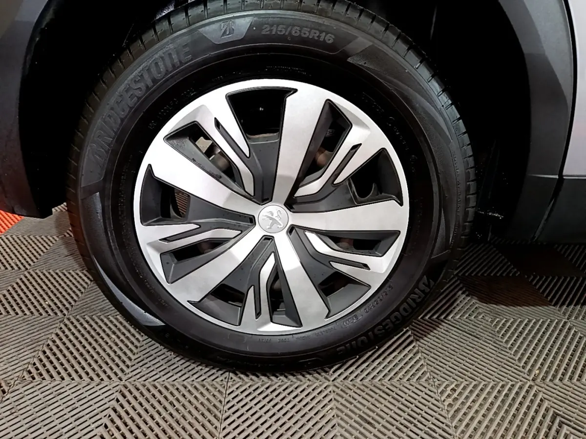 Gros plan sur la roue avant droite d’un Peugeot 2008 gris clair, avec jante alliage et pneu Bridgestone.