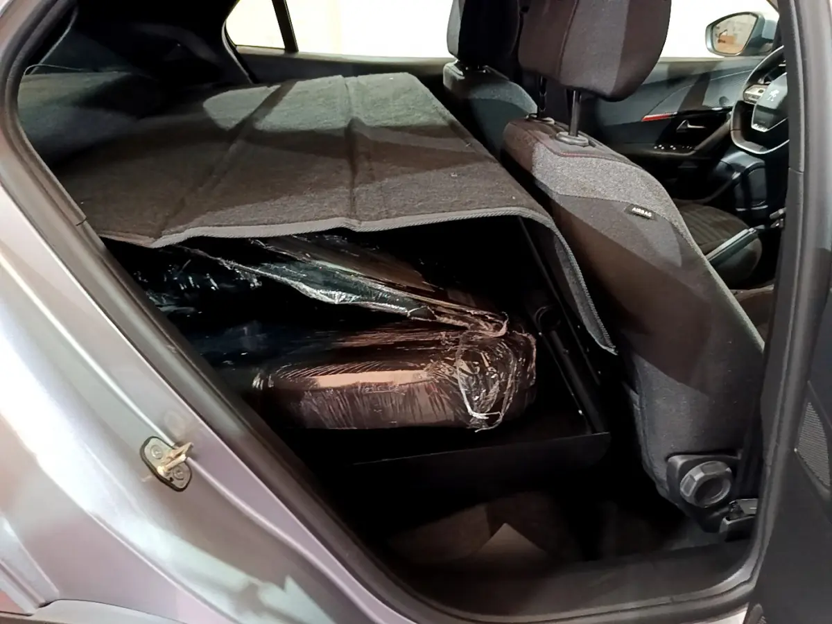 Vue intérieure côté gauche du Peugeot 2008 gris clair 2022, sièges arrière rabattus avec chargement protégé par une couverture.