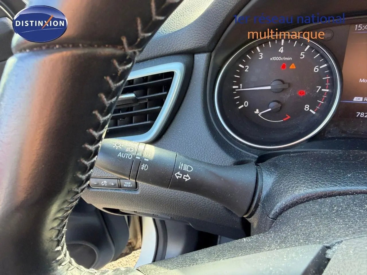 Détail du volant et du combiné d'instruments du Nissan Qashqai blanc nacré, montrant les commandes d'éclairage et le compte-tours.