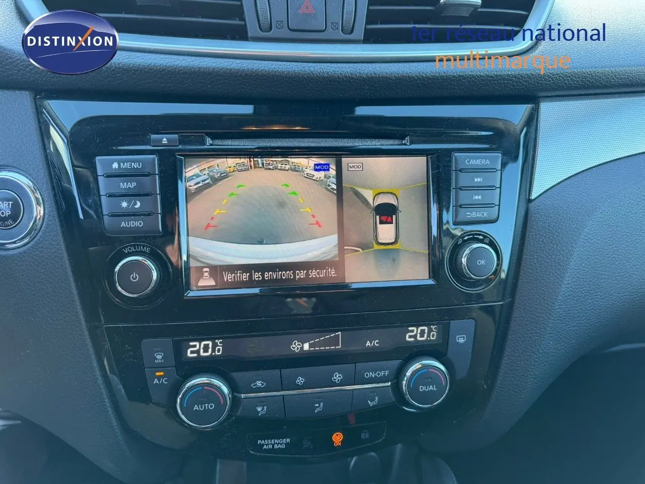 Vue rapprochée de la console centrale du Nissan Qashqai blanc nacré, avec écran de caméra de recul et commandes climatisation.