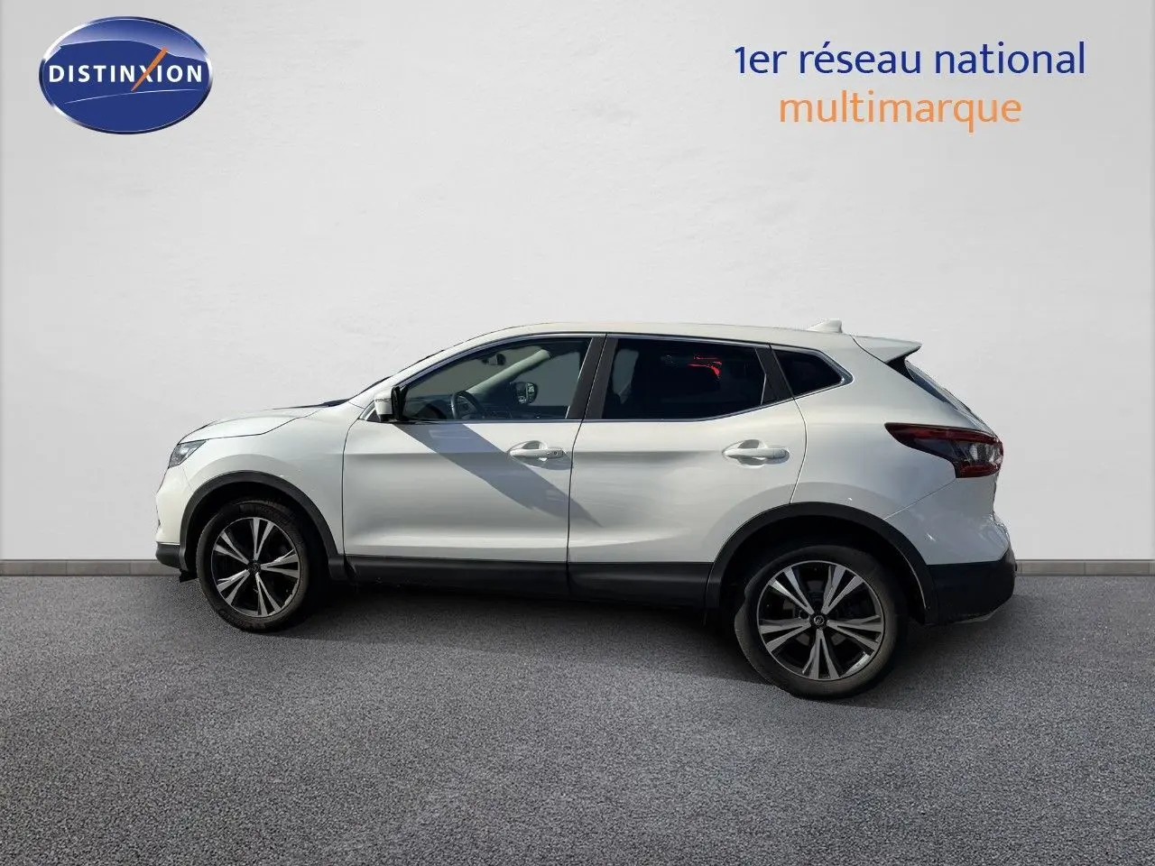 Vue de profil côté gauche d'un Nissan Qashqai blanc nacré avec jantes alliage noires et détails noirs sur bas de caisse.