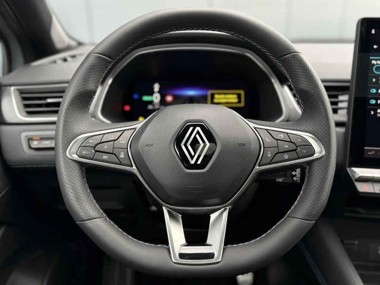 Vue rapprochée du volant en cuir noir avec surpiqûres tricolores du Renault Captur E-Tech Full Hybrid 2025.