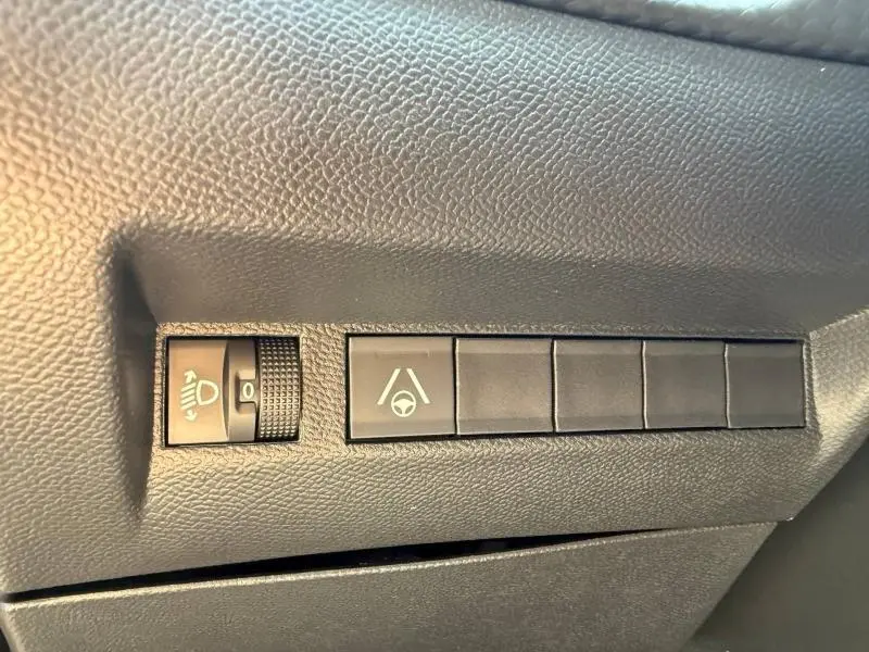 Gros plan sur les commandes de réglage des phares et d’aide au maintien de voie dans l’habitacle du Peugeot 2008 rouge Elixir.