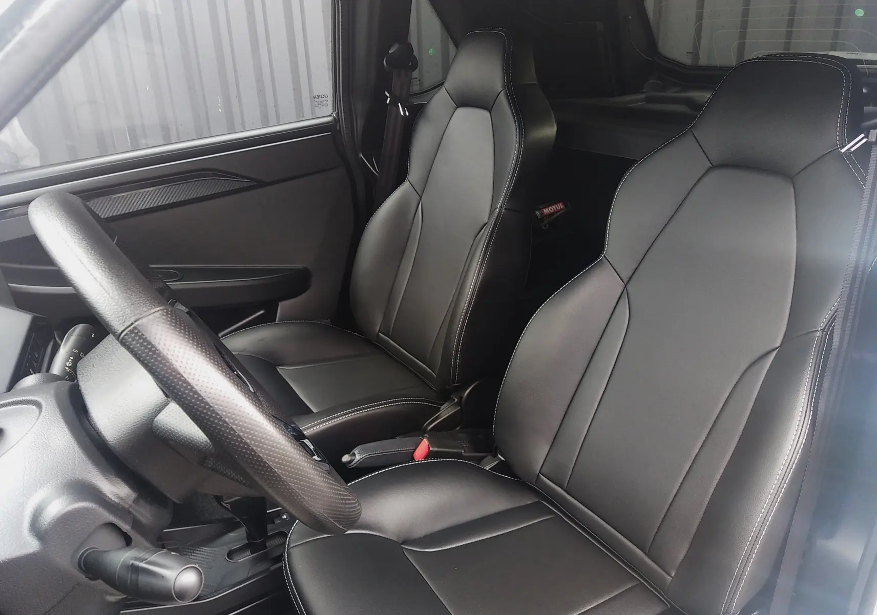 Vue intérieure côté gauche du LIGIER JS50 REVO D+ Select 2026, sièges en cuir noir avec surpiqûres blanches.
