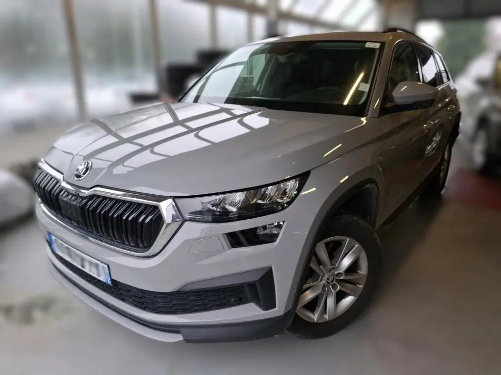 Vue 3/4 avant droit d'un Skoda Kodiaq gris clair 2023, mettant en valeur sa calandre distinctive et ses phares modernes.