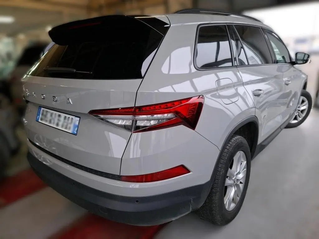 Vue 3/4 arrière droite d’un Skoda Kodiaq gris clair 2023 avec feux arrière LED et toit noir brillant.