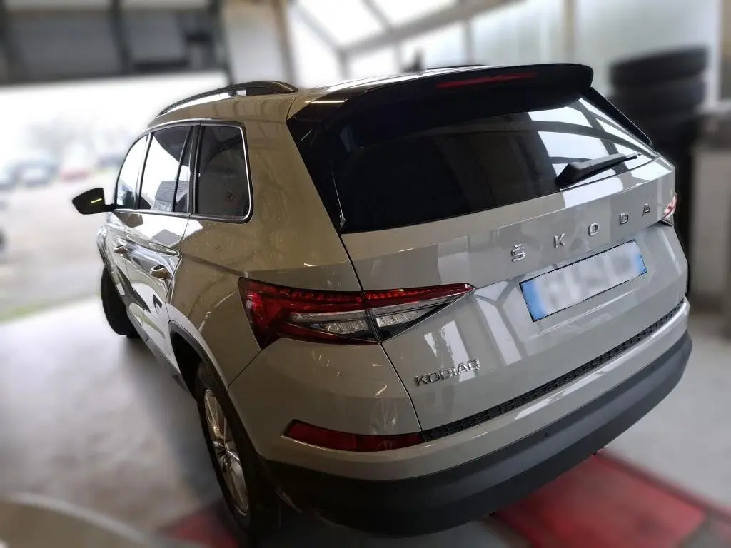 Vue 3/4 arrière droite d'un Skoda Kodiaq gris clair 2023 avec feux arrière LED et toit noir brillant.