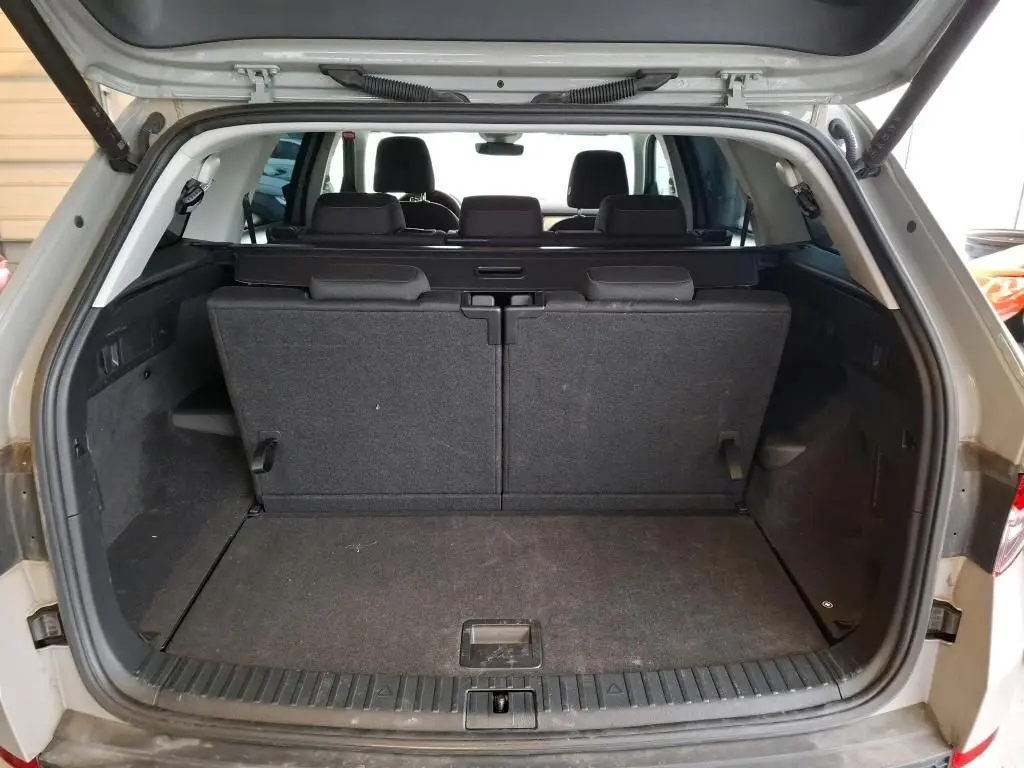 Vue arrière du coffre ouvert d'un Skoda Kodiaq gris clair 2023, montrant la troisième rangée de sièges relevée.