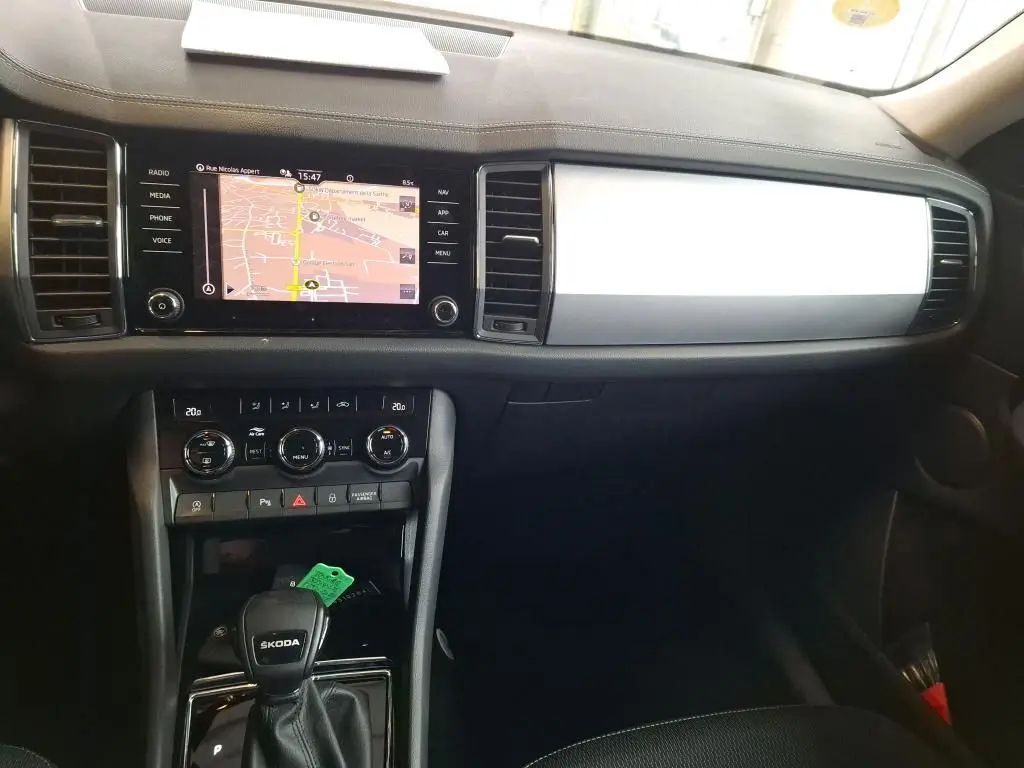 Vue intérieure du tableau de bord et console centrale du Skoda Kodiaq gris clair, avec écran tactile et commandes climatisation visibles.