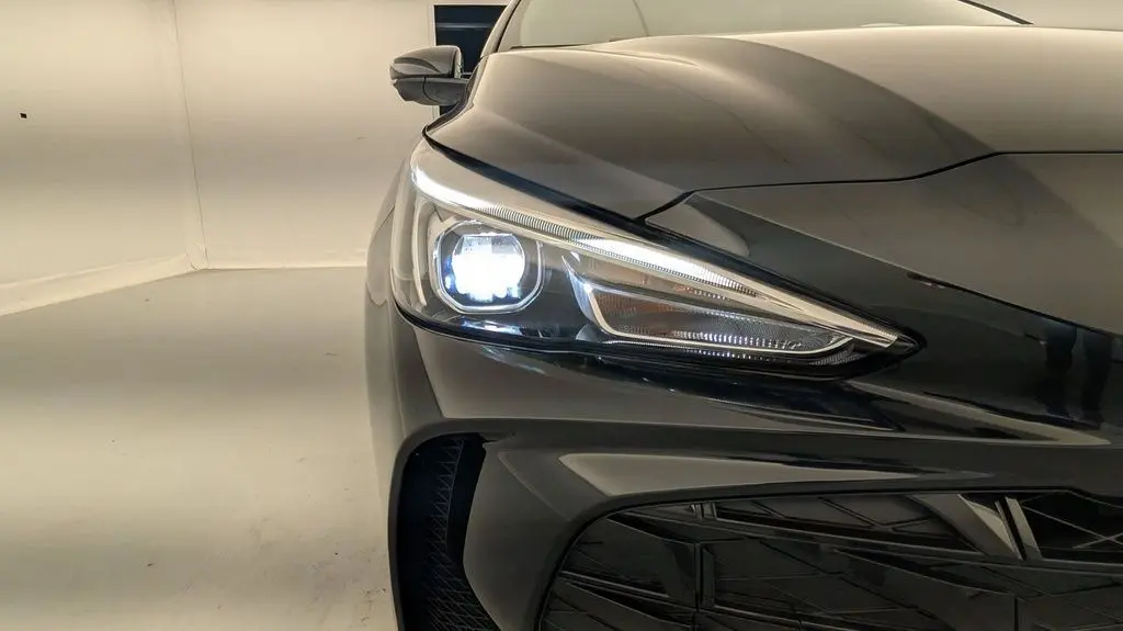 Gros plan sur le phare avant gauche allumé du MG3 Pebble Black 2026, mettant en valeur la calandre et la peinture métallisée.
