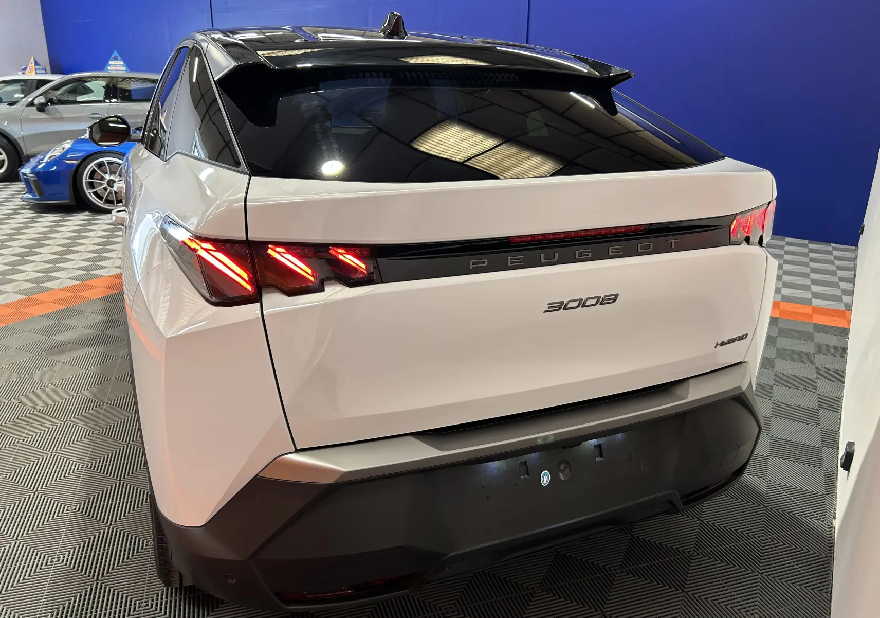 Vue 3/4 arrière droite du Peugeot 3008 blanc Okenite avec feux arrière LED distinctifs et toit noir brillant.