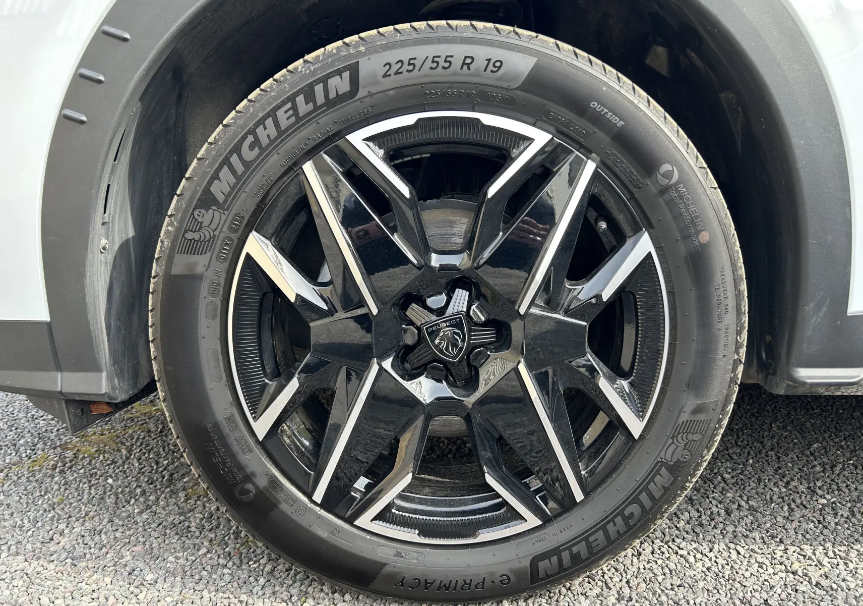 Gros plan sur la roue avant gauche du Peugeot 3008 blanc Okenite, jante alliage noire et argent avec pneu Michelin.