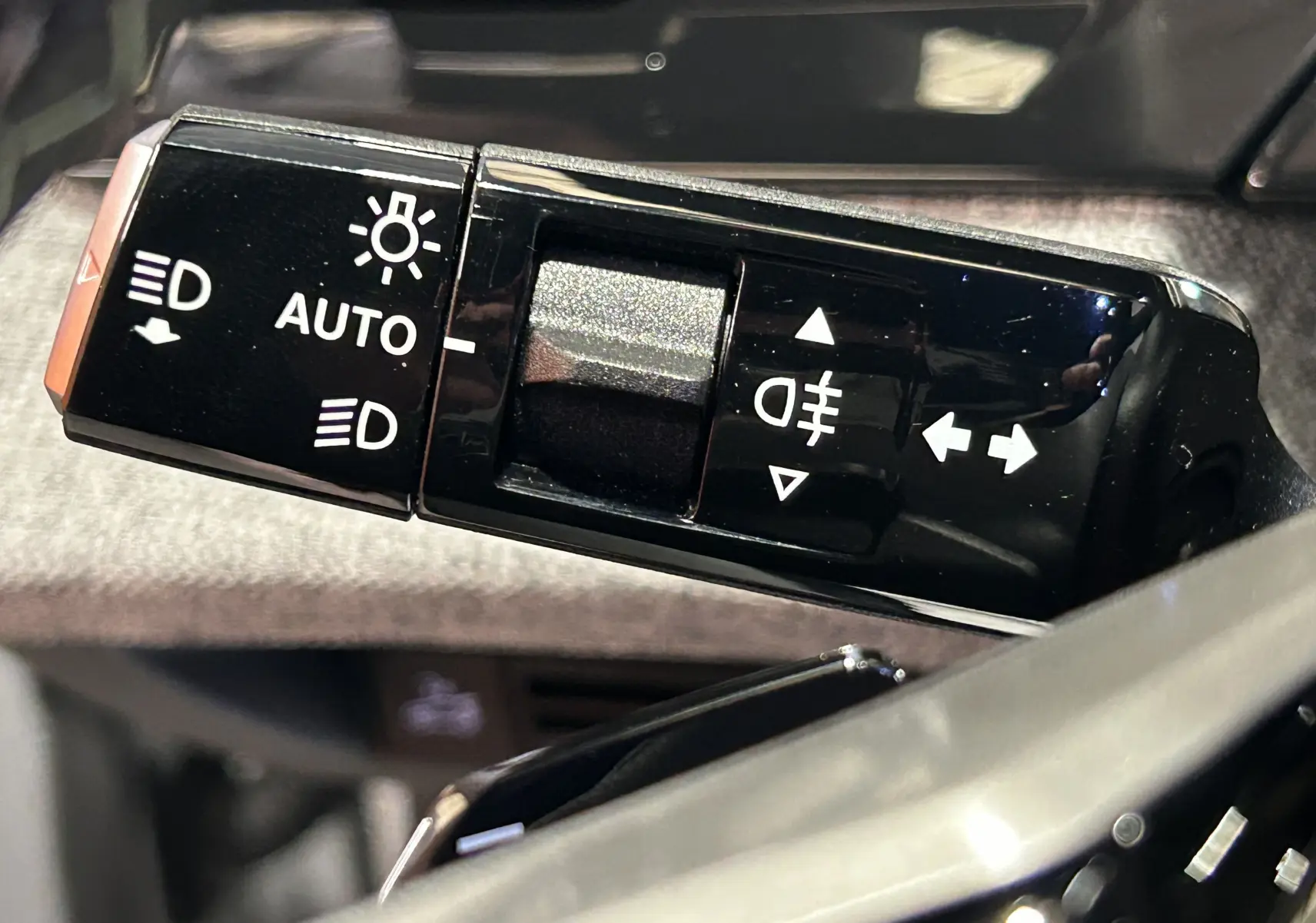 Gros plan sur la commande des feux et clignotants du Peugeot 3008 III Hybrid blanc, avec réglage automatique des phares.