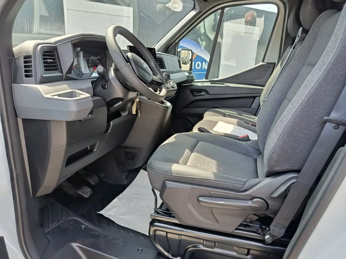 Vue intérieure côté conducteur du Renault Master 2025, sièges gris et tableau de bord avec écran tactile.