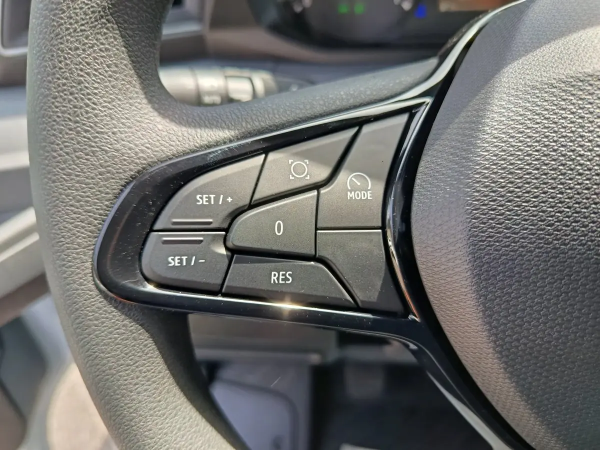 Gros plan sur les commandes de régulateur de vitesse au volant du Renault Master, boutons noirs sur fond gris texturé.