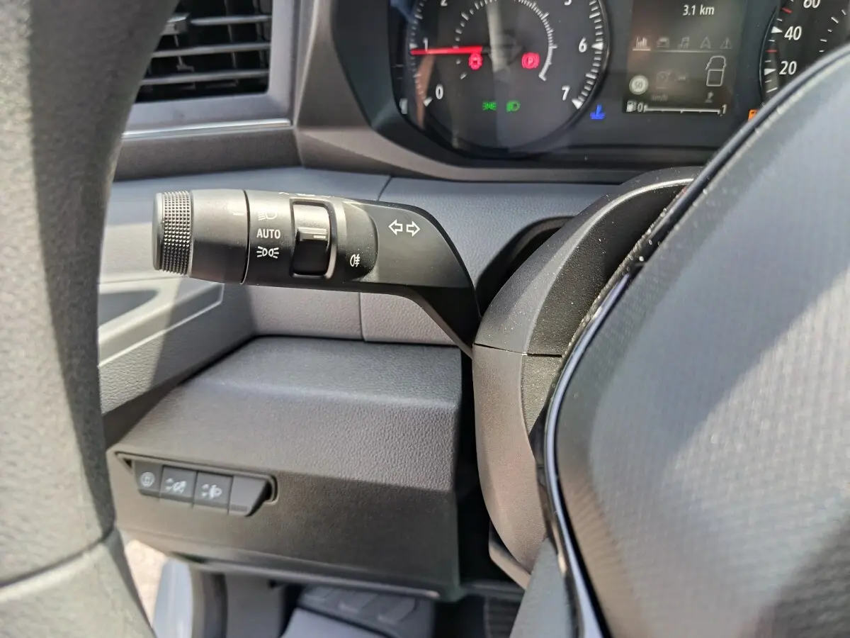 Gros plan sur la manette de clignotant noire et le tableau de bord du Renault Master 2025, intérieur gris foncé.
