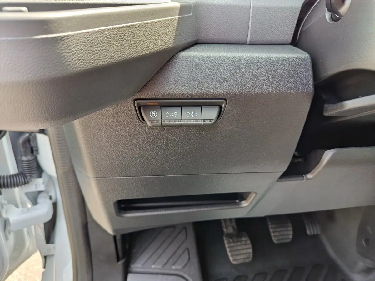 Détail intérieur côté gauche du tableau de bord noir avec commandes de réglage des phares et verrouillage sur Renault Master blanc.