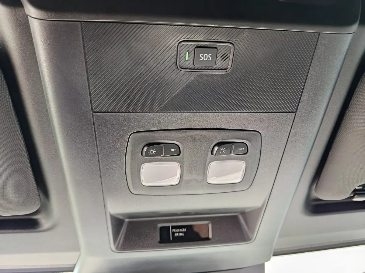 Vue en contre-plongée du plafonnier intérieur gris avec boutons d’éclairage et bouton SOS du Renault Master blanc 2025.
