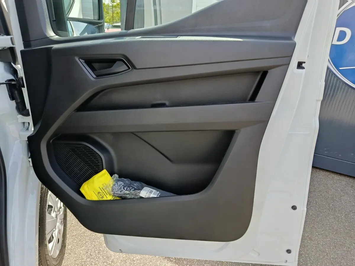 Vue rapprochée de la porte avant gauche blanche du Renault Master avec rangement et haut-parleur intégré.