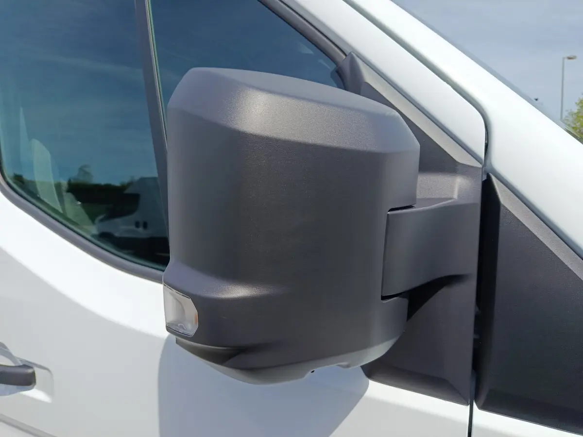 Gros plan sur le rétroviseur droit noir du Renault Master blanc, avec fenêtre latérale en arrière-plan.