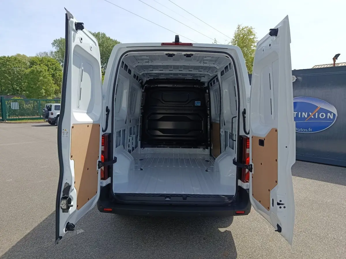 Vue arrière d’un Renault Master blanc 2025 avec portes arrière ouvertes montrant l’espace de chargement vide et protégé.