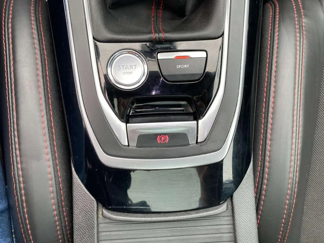 Vue rapprochée de la console centrale noire avec bouton Start/Stop et mode Sport sur Peugeot 308 rouge GTi 2016.