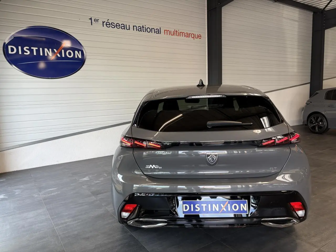 Vue arrière d'une Peugeot 308 GT gris selenium avec feux arrière LED et bandeau noir brillant.