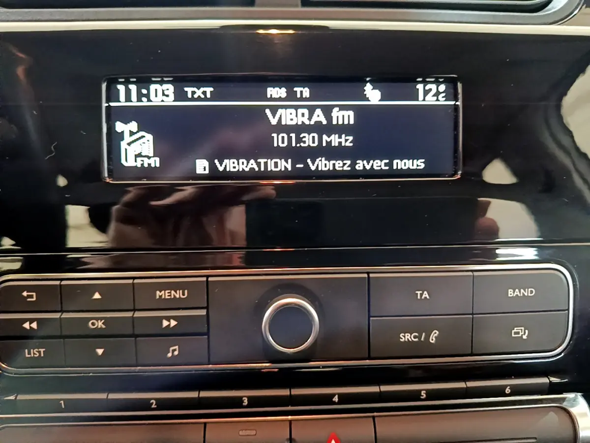Détail de la console centrale noire de la Citroën C3 blanche, affichant la radio VIBRA fm à 101.30 MHz