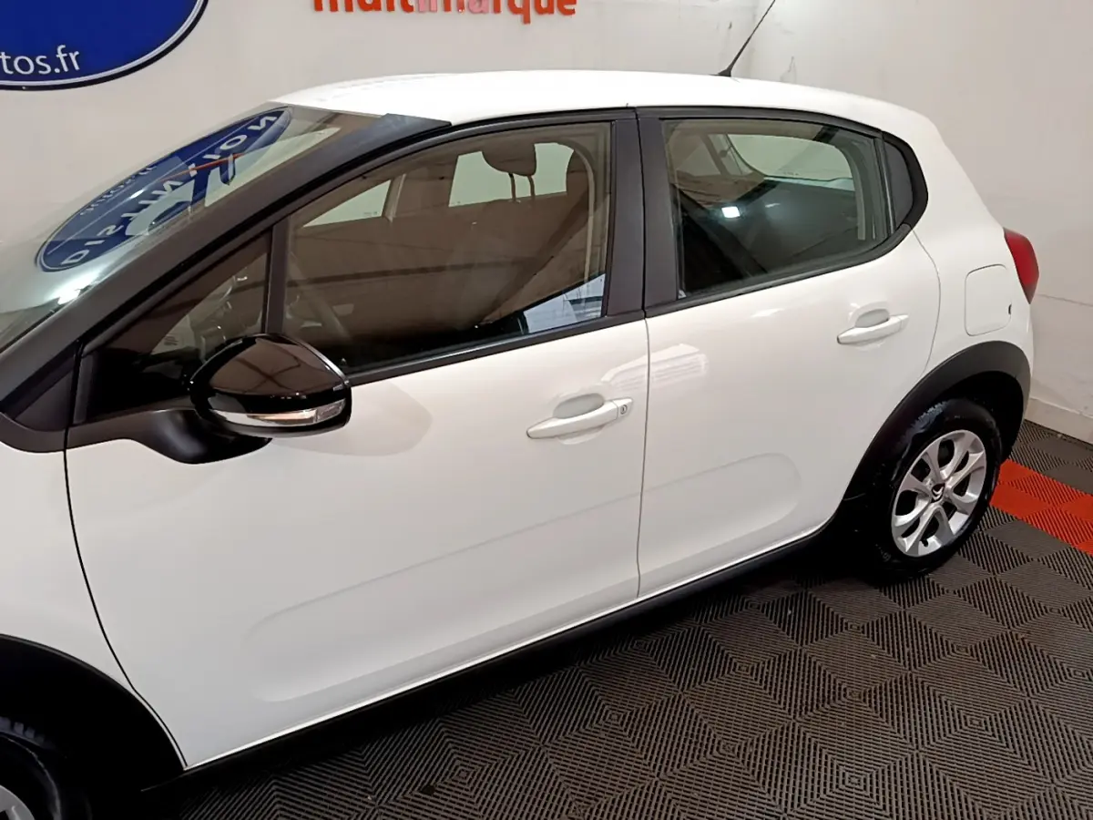 Profil côté gauche d'une Citroën C3 blanche 2018 avec rétroviseurs noirs et jantes alliage visibles en intérieur showroom.