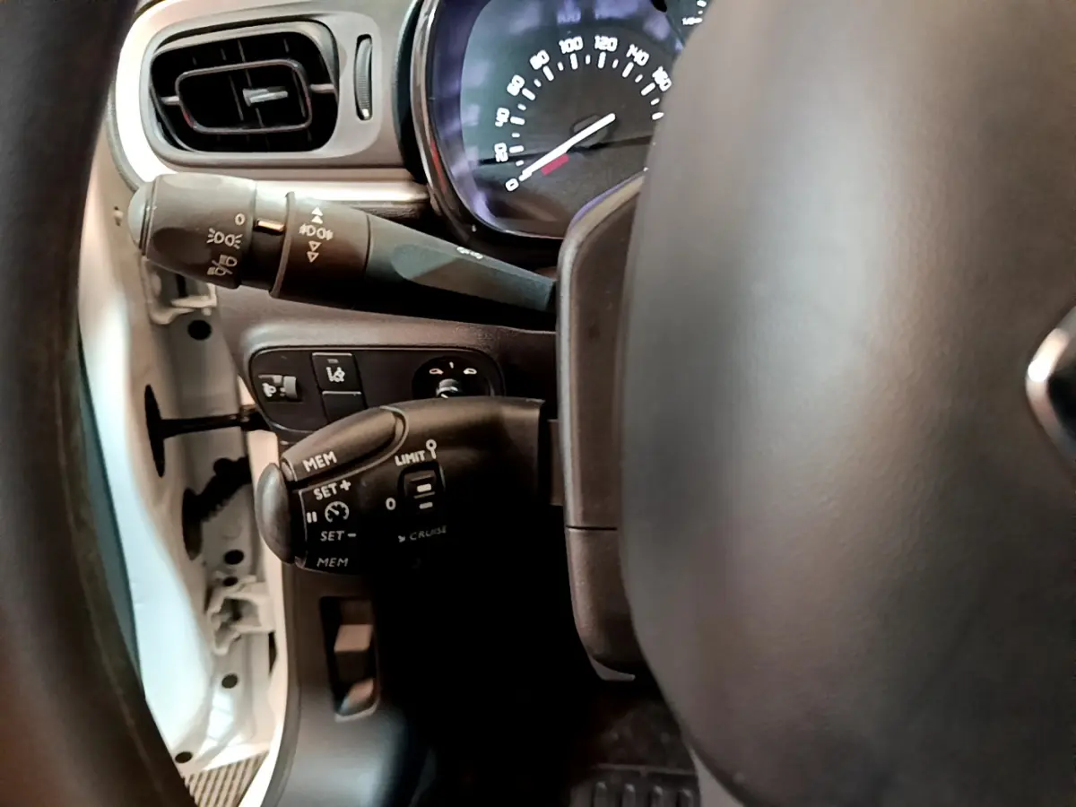 Vue rapprochée du volant et des commandes de régulateur de vitesse d'une Citroën C3 blanche de 2018.