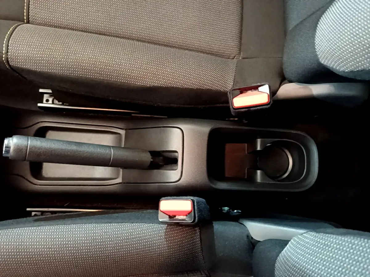 Vue plongeante sur la console centrale noire de la Citroën C3 2018, montrant frein à main et ceintures rouges.