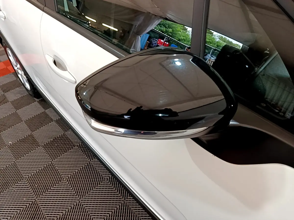 Rétroviseur noir brillant côté gauche d'une Citroën C3 blanche PureTech 68 BVM Feel vue en gros plan intérieur garage.