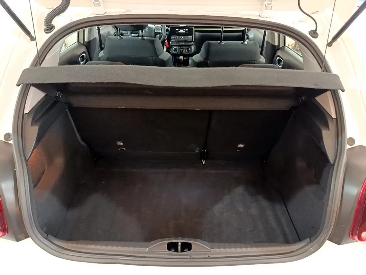 Coffre ouvert d'une Citroën C3 blanche vue de l'arrière, montrant l'espace de chargement et l'intérieur noir des sièges avant.